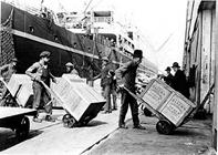 Longshoremen unloading cargo from a freighter by handtruck, 1906